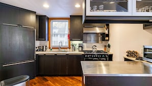 Una cocina moderna con armarios oscuros, electrodomésticos de acero inoxidable y suelo de madera.