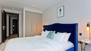 Habitación de hotel con una cama grande, una mesita de noche con lámpara, un armario y un cuadro enmarcado en la pared.