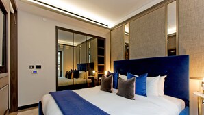 Una habitación de hotel moderna con una cama grande, un espejo y una mesita de noche.