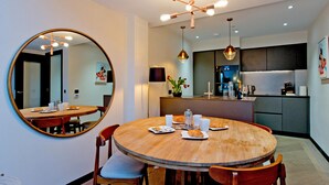 Un comedor moderno con una mesa redonda de madera, sillas y un espejo grande en la pared.