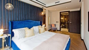 Una habitació d'hotel moderna amb un llit gran, una taula de nit, una cadira i un armari.