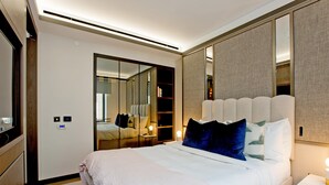 Una camera d'albergo moderna con un grande letto, un armadio, uno specchio e un comodino con una lampada.