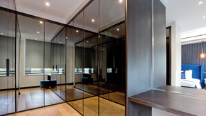 Une chambre d’hôtel moderne dotée d’une grande porte-fenêtre coulissante, d’un plancher en bois et offrant une vue sur le paysage urbain.
