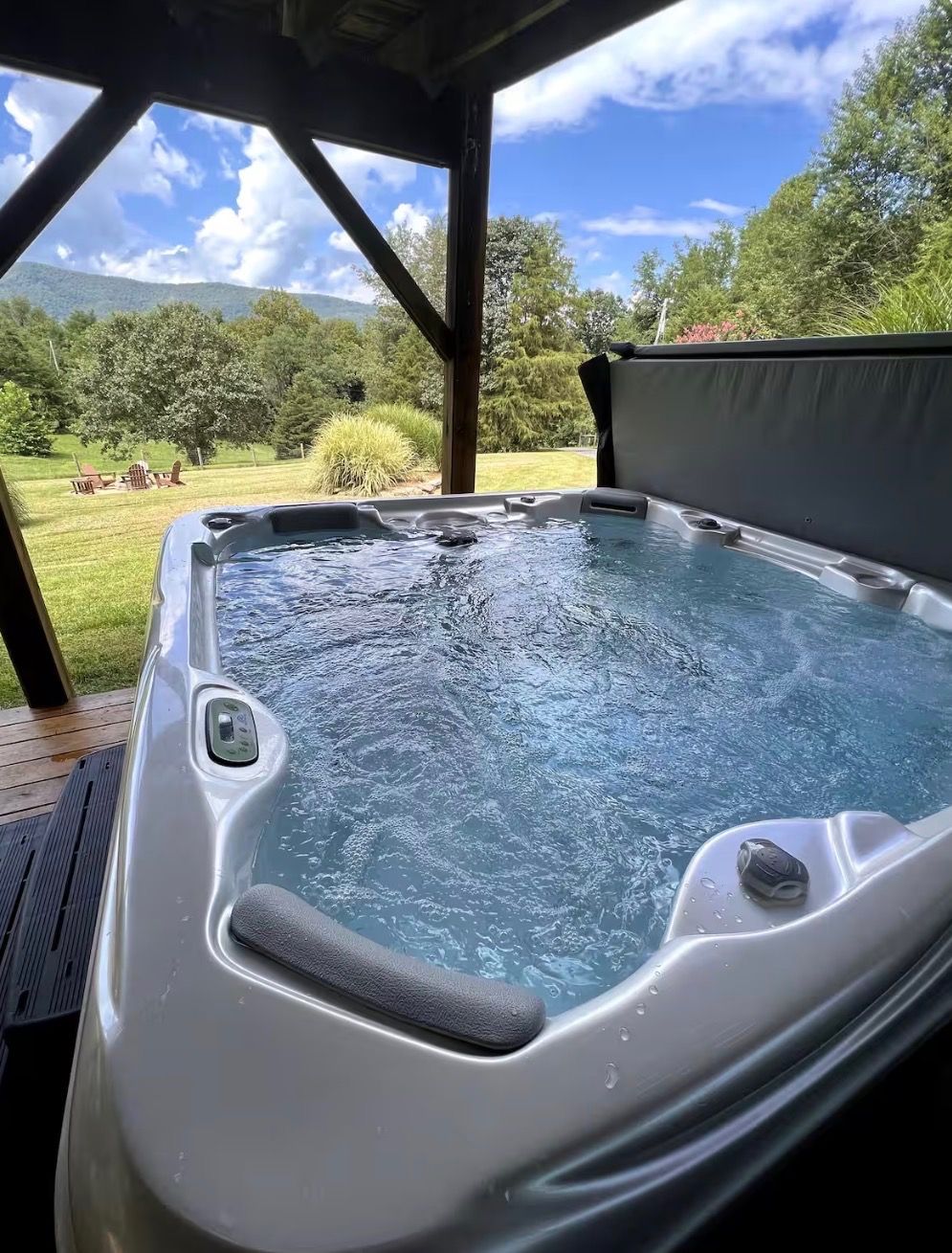 A hot tub with a view of a grassy landscape and trees.