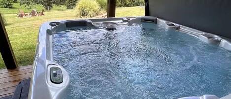 A hot tub with a view of a grassy landscape and trees.