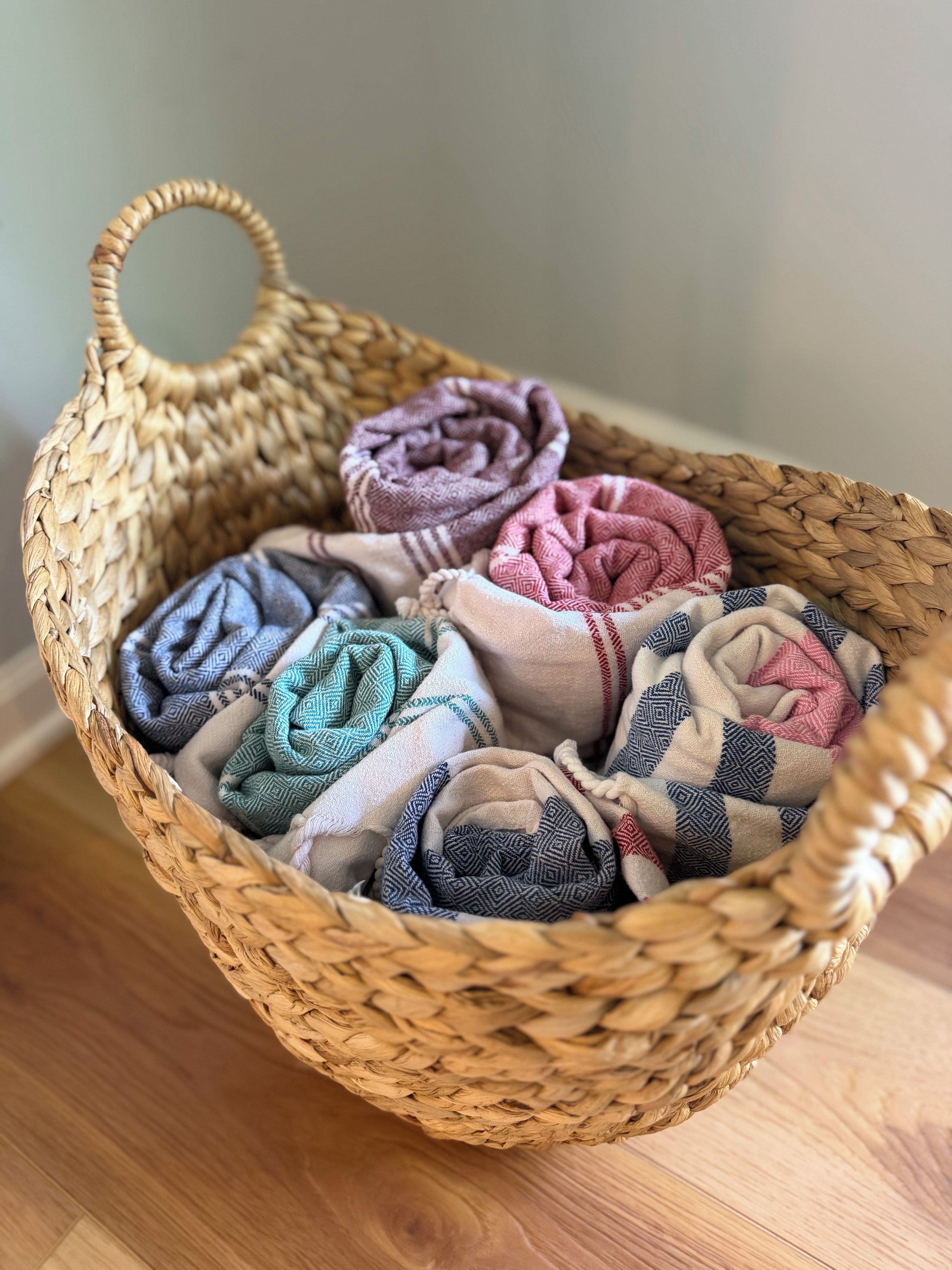 A woven basket containing rolled-up blankets with various patterns.