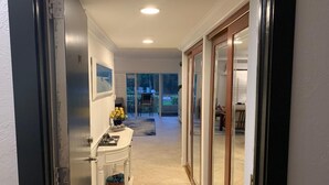 Un couloir avec une armoire blanche, une porte vitrée et une vue sur un coin repas.
