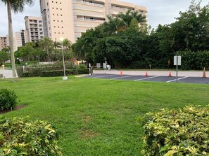 Una zona erbosa con un vialetto lastricato, circondata dal verde e con un edificio a più piani sullo sfondo.