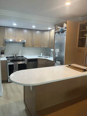 A modern kitchen with stainless steel appliances, a white marble countertop, and wooden cabinets. - LOCATION, LOCATION, LOCATION! Studio apt Full kitchen, WiFi, 2 min walk to beach (Naples)