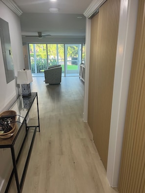 A hallway with a ceiling fan, a patterned lamp, a wooden sideboard, and a view of a patio with a couch. - LOCATION, LOCATION, LOCATION! Studio apt Full kitchen, WiFi, 2 min walk to beach (Naples)