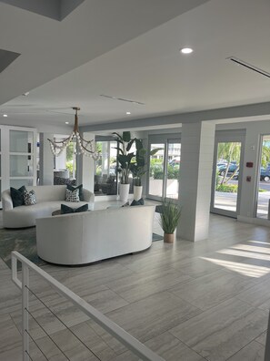 A modern lobby with a reception desk, seating area, and large windows. - LOCATION, LOCATION, LOCATION! Studio apt Full kitchen, WiFi, 2 min walk to beach (Naples)