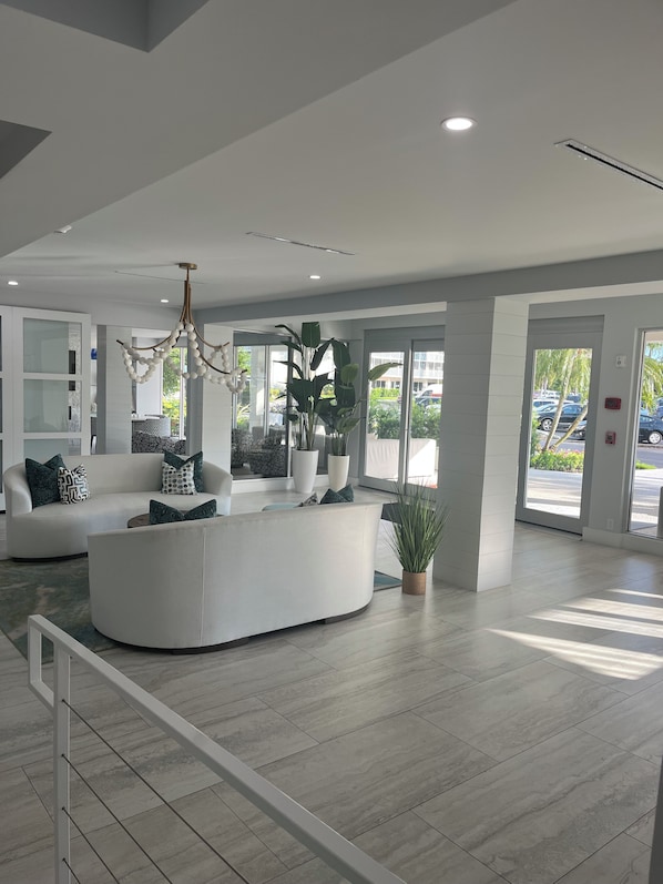A modern lobby with a reception desk, seating area, and large windows.