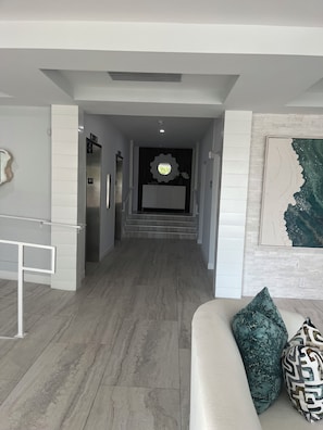 A modern interior with a staircase leading to a second floor, a white sofa with patterned cushions, and a decorative wall piece. - LOCATION, LOCATION, LOCATION! Studio apt Full kitchen, WiFi, 2 min walk to beach (Naples)