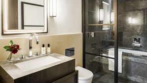 Een moderne badkamer met een groot wastafelmeubel, spiegel en een douchecabine met glazen wanden.