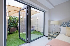 A modern bedroom with a sliding glass door leading to a patio area. - 2-bed Deluxe 104 (London)