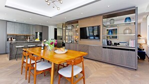 Une cuisine moderne avec une table à manger en bois, des appareils électroménagers intégrés et un grand îlot central.