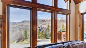 A room with large windows, a leather sofa, and a view of a mountainous landscape. - Russell Home by AvantStay | Expansive Deck, Stunning Views & Hot Tub! (Telluride)