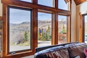 A room with large windows, a leather sofa, and a view of a mountainous landscape.