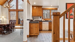 A spacious kitchen with wooden cabinets, a dining area with a table and chairs, and a staircase leading to another level. - Russell Home by AvantStay | Expansive Deck, Stunning Views & Hot Tub! (Telluride)