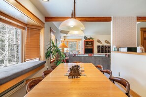 Un comedor con mesa de madera, sillas, un banco y una lámpara colgante.