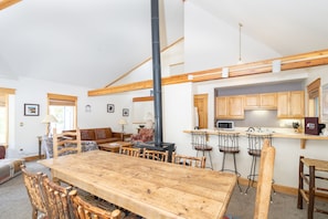 Cozy dining area with a large table and comfortable seating, fireplace, and fully equipped kitchen.