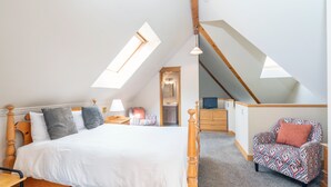 Une chambre à coucher avec un lit en bois, une chaise, un bureau et une lucarne.