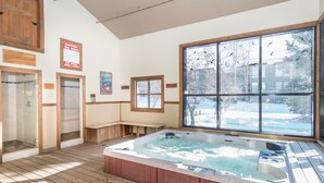 A spa area with a hot tub, wooden benches, and a large window with a view of trees. - Telluride Lodge 311 by AvantStay | Close to Slopes & Town! (Telluride)