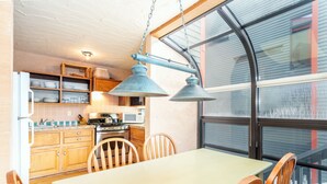 Une cuisine avec des meubles de rangement en bois, une table à manger et des chaises. Il y a une fenêtre donnant sur l’extérieur.