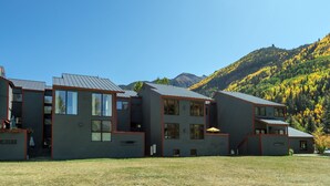 Edificio moderno con varias unidades, ventanas amplias y techo plano, con la silueta de una montaña boscosa al fondo.
