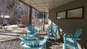 A covered patio area with several Adirondack chairs, a concrete bench, and a small table. - Viking Lodge 103 by AvantStay | Stunning Condo, Near Ski Lift (Telluride)