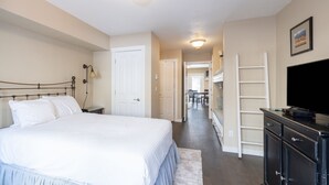 Ein Schlafzimmer mit einem großen Bett, einem Schminktisch, einem Fernseher und einem Flur, der in einen Essbereich führt.