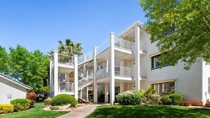Un edificio residencial de varios pisos con una escalera central, balcones y un césped bien cuidado.