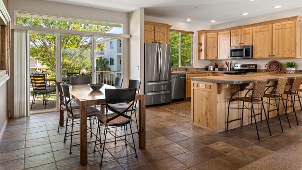 Una cocina moderna con armarios de madera, electrodomésticos de acero inoxidable y una isla grande con taburetes de bar.