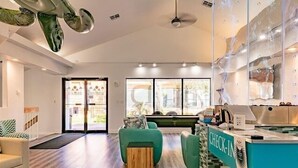 Un interior moderno con mostrador de recepción, suelo de madera y una zona de estar con sillas verdes.