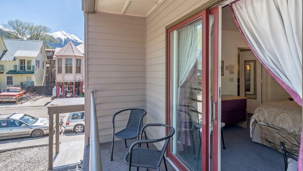 Un balcon avec deux chaises, un lit à baldaquin et une vue sur une montagne.