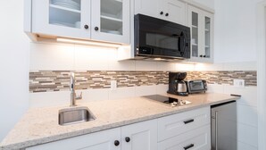 A modern kitchen with white cabinets, a stainless steel sink, a black microwave, and a coffee maker. - Viking Lodge 216 by AvantStay | Great Ski Access, Walk to Downtown (Telluride)