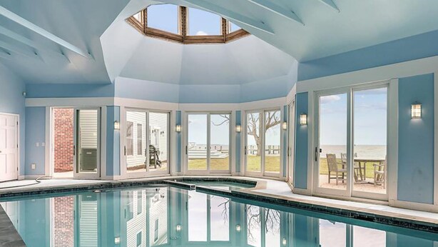 A large indoor swimming pool with a skylight, large windows, and a view of the outdoors. - Tilghman Waterfront | Indoor Pool | Private Dock | Pool House (Tilghman)
