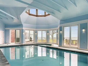 Un'ampia piscina coperta con lucernario, grandi finestre e vista sull'esterno.