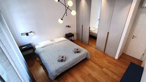 A modern bedroom with a bed, bedside tables, a hanging light fixture, and a wardrobe. - Apartment Freyja (Split)