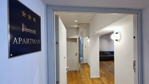 An interior hallway leading to a living area with a sofa, a sign indicating 'APARTMAN', and a mirror reflecting the room. - Apartment Freyja (Split)