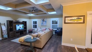 A living room with a TV, sofa, and a ceiling fan. - Cheerful 2 bed 1 bath w/patio. 10 min from beach,  dog friendly! (Navarre)