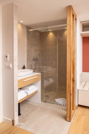A modern bathroom with a glass-enclosed shower, a wooden vanity, and a white sink. - Cueillette (Altillac)