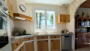 Eine Küche mit Holzausstattung, einem eingebauten Backofen, einer Spüle und einem Fenster mit Blick auf Bäume.