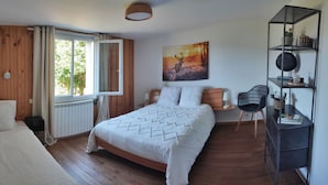 Ein Schlafzimmer mit einem hölzernen Kopfteil, einem großen Bett mit gemustertem Überwurf, einem Fenster mit Vorhängen, einem Wandregal mit Dekoration und einem Bild von einem Reh.