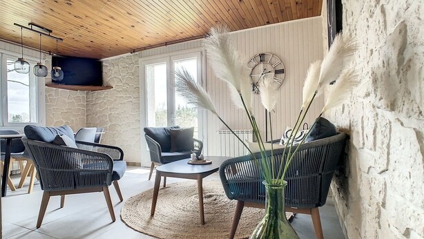 Ein gemütliches Wohnzimmer mit Korbmöbeln, einem runden Couchtisch und einer dekorativen Vase mit Federn.