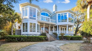 Une grande maison à deux étages, dotée d’un porche avant imposant, de nombreuses fenêtres et d’une allée incurvée.