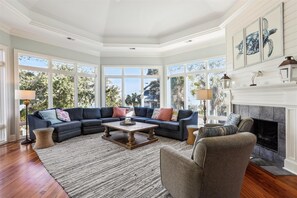 A spacious living room with a large sectional sofa, a fireplace, and large windows offering a view of the outdoors. - 4 Brigantine, 2nd Row, Large Private Pool, Free Golf, Pickleball (Hilton Head Island)