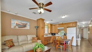 A living room with a sofa, coffee table, and dining area with chairs. - *Cottage #3 @ Fisherman's Landing (boat shelter)* (Langston)