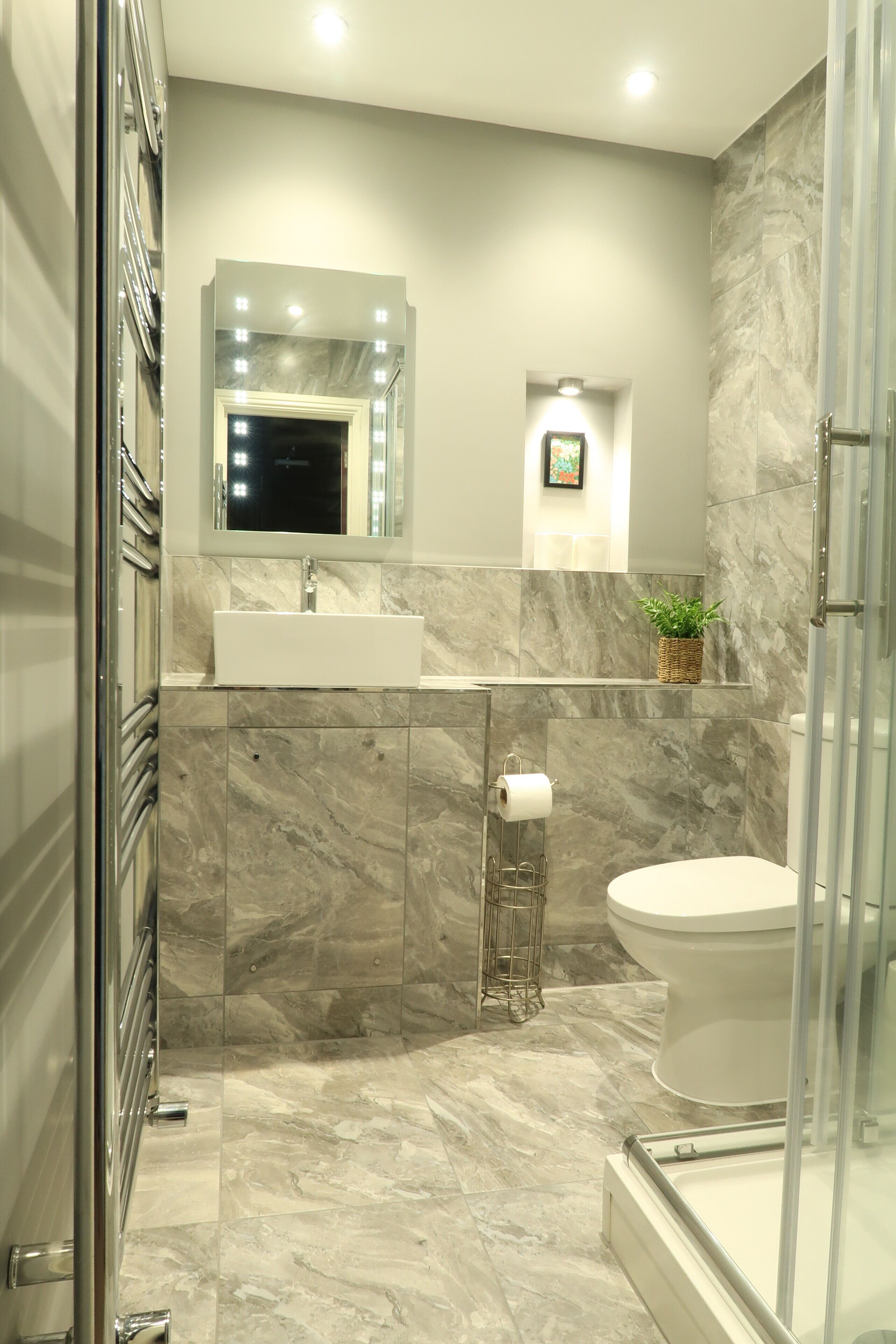 A modern bathroom with a large mirror, a sink, a toilet, and a shower area.