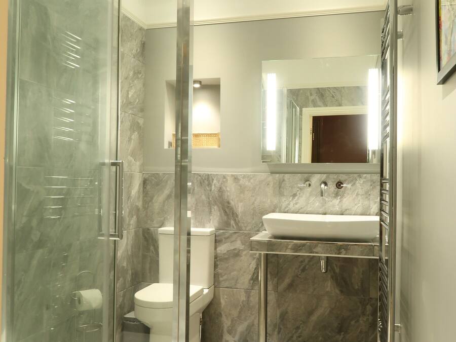 Une salle de bain moderne avec une douche en verre, un lavabo blanc et un sol carrelé en marbre.